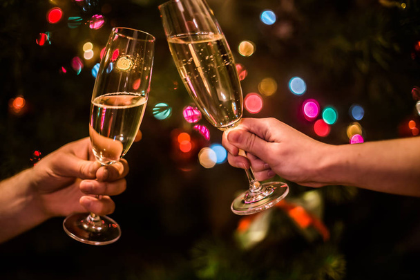 Glass with champagne in hand on a Christmas tree background - Photo, Image