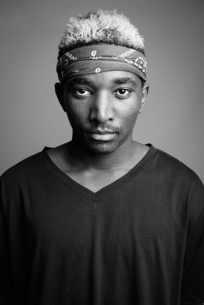 Joven hombre africano vistiendo bandana como diadema sobre fondo gris
 - Foto, Imagen