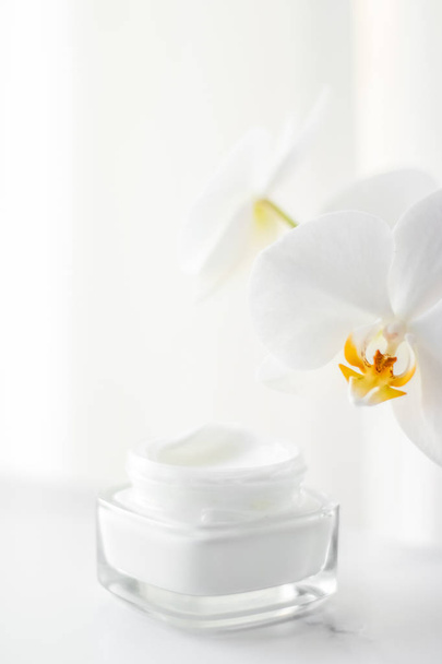 Face cream moisturizer jar and orchid flower, moisturizing skin  - Foto, afbeelding