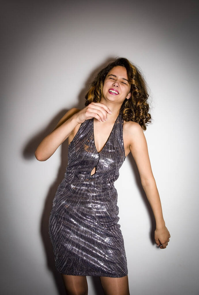Young young woman in silver dress laughing and having fun. Isolated on gray. - Fotografie, Obrázek
