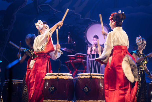 Hagyományos japán előadás. Színésznők csoportja hagyományos fehér és piros kimonóban és róka maszkban dobol a színpadon. - Fotó, kép