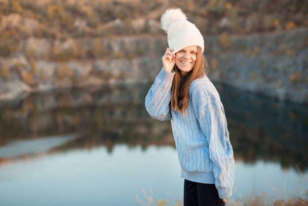 Retrato de inverno de mulher sorridente em chapéu branco com grande bubo faz cara engraçada
 - Foto, Imagem
