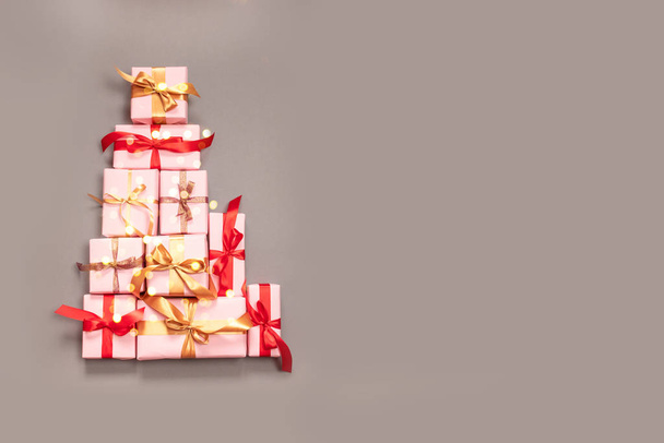 Kerst decoratieve compositie met papier geschenkdoos, gouden ballen, gouden lint strik en confetti op grijze achtergrond. Flat lay, bovenaanzicht voor vakantie winkelen op boksdag - Foto, afbeelding
