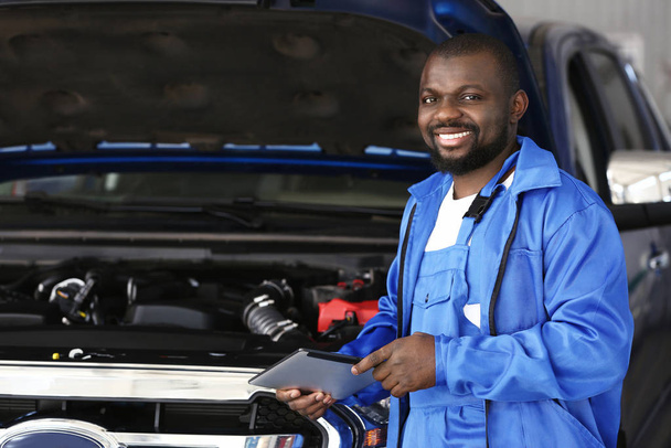 Afroamerykanin mechanik z tabletem pracujący w centrum obsługi samochodów - Zdjęcie, obraz