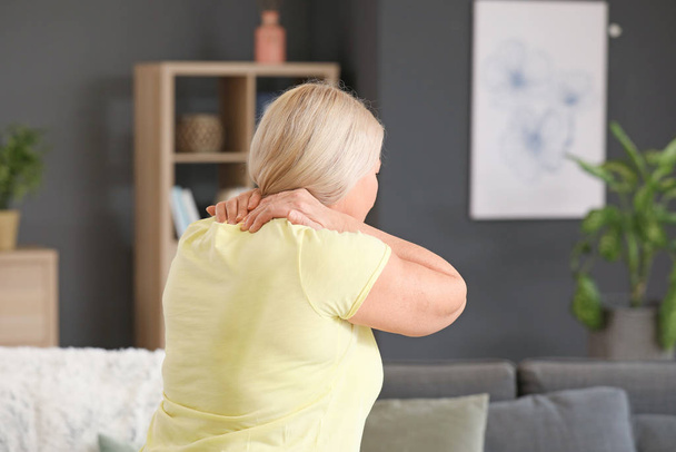 Mujer madura que sufre de dolor en el cuello en casa
 - Foto, imagen