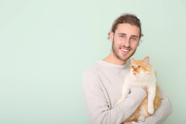 Man with cute cat on color background - Фото, зображення