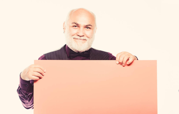 Senior means experienced. Senior man recommend something. Elderly people. Senior holding blank sign board and looking at camera. Man bold head and gray beard hold poster for advertisement copy space - Photo, Image