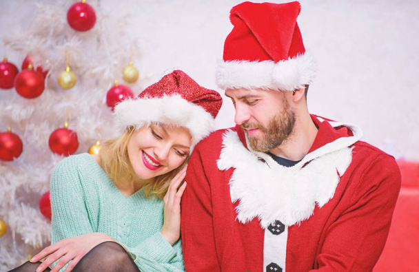 Loving couple cuddle smiling while waiting for santa christmas tree background. Christmas magical time. We love christmas. Couple in love enjoy christmas holiday celebration. Family wear santa hats - Fotoğraf, Görsel