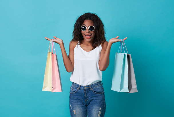 Happy beautiful young woman hand holding shopping bag isolated over blue background. - Foto, Bild