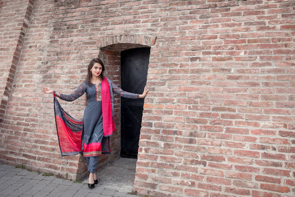Dívka v tradičním indickém oblečení, Salwar Kameez. Indická dívka v tradičním oděvním stánku u vchodu do domu. - Fotografie, Obrázek