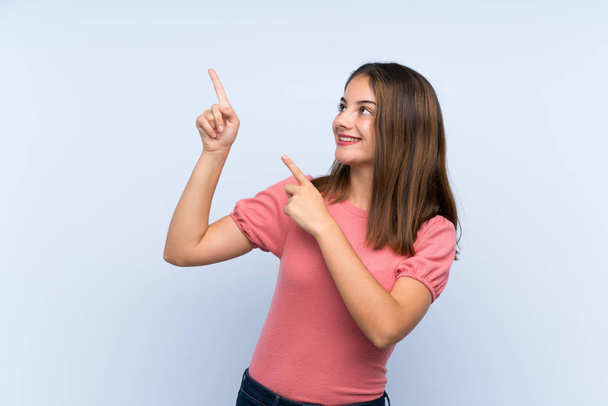 jong brunette meisje over geïsoleerd blauw achtergrond wijzend met de index vinger een geweldig idee - Foto, afbeelding