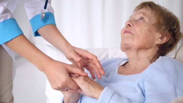 Dokter geruststellend senior patiënt die handen vasthoudt. Oudere gezondheidszorg. - Video