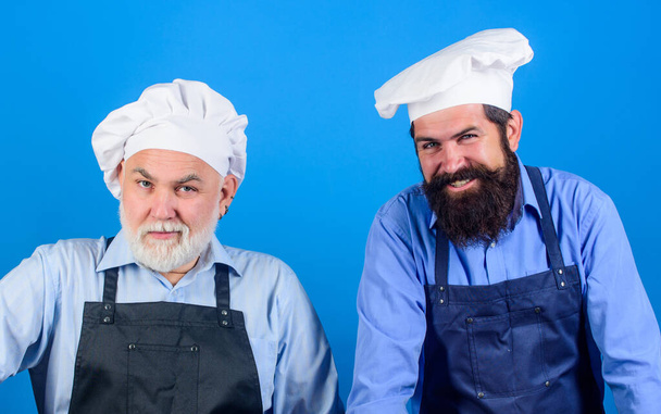 Cafe workers. Restaurant kitchen. Culinary industry. Restaurant staff. Father and son culinary hobby. Family restaurant. Mature bearded men professional restaurant cooks. Chef men wear aprons - Foto, Imagen