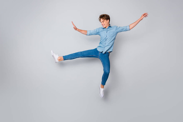 Full length photo of cheerful candid man jump raise hands legs imagine he child teen again wear casual style sneakers isolated over grey color background - Photo, image