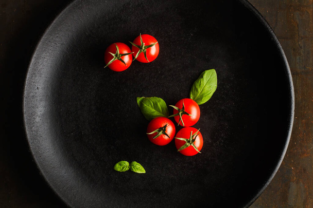 Красные помидоры черри на черной тарелке
 - Фото, изображение