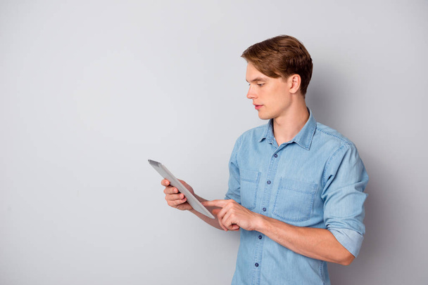 Profile side photo of concentrated man use tablet search websites for education college university project report stand copyspace wear trendy clothing isolated over grey color background - 写真・画像