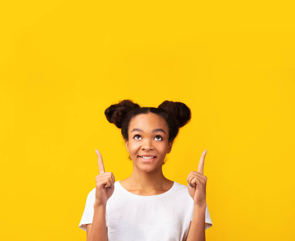 Excited black girl looking and pointing up - Photo, Image