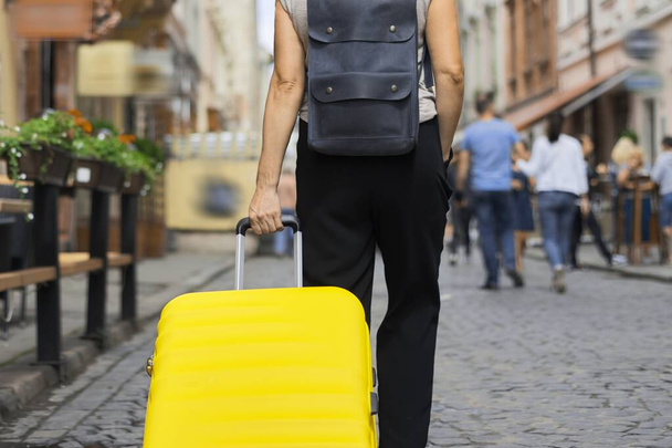 Luggage travel tourism concept, closeup of yellow suitcase in hand of walking woman - Valokuva, kuva