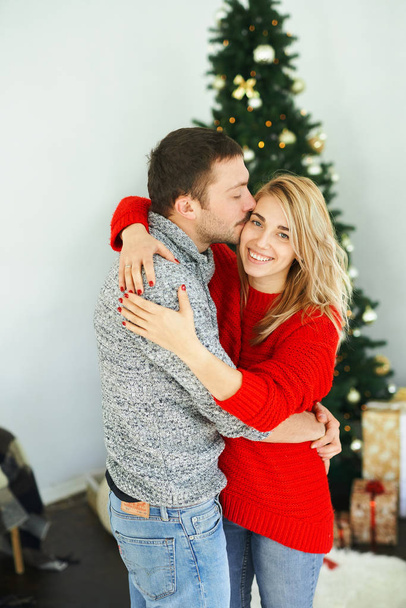 Romantic couple in love embracing, kissing near the Xmas tree at home. - Foto, Bild