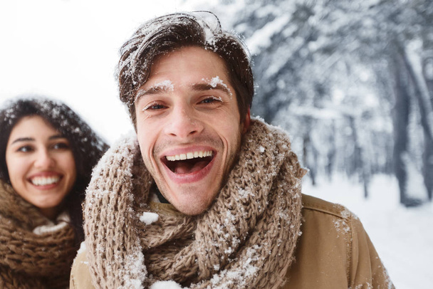hombre sonriendo a cámara caminando con novia en invierno bosque
 - Foto, Imagen