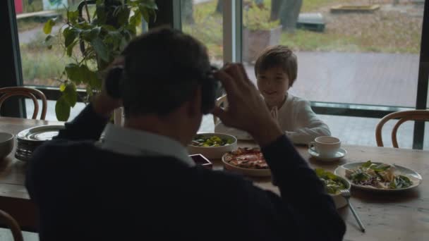 Vater setzt beim Mittagessen mit Sohn Virtual-Reality-Brille auf - Filmmaterial, Video