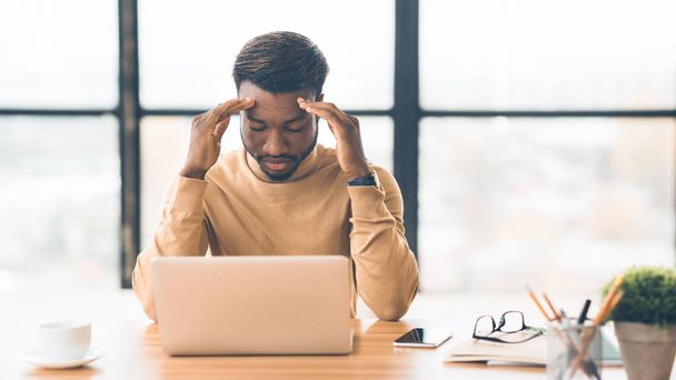 Exhausted millennial black businessman having migraine attack - Foto, afbeelding