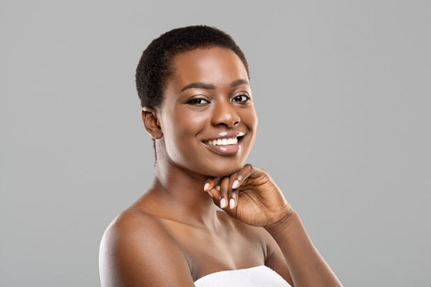 Портрет красивой черной женщины, улыбающейся и трогающей подбородок
 - Фото, изображение