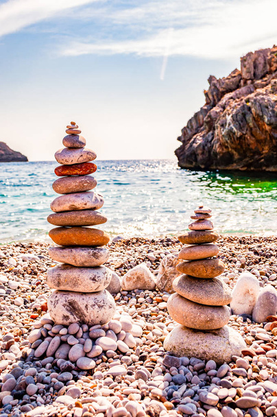 Дві вежі з плоских каменів на пляжі. Балансування каменю - це художня дисципліна, або хобі, в якій камені природно зрівноважуються один над одним в різних положеннях. Кала Б "янка Італія - Фото, зображення