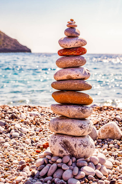 A torre de pedras planas na praia. Balanceamento de pedra é a disciplina de arte, ou hobby em que rochas naturalmente equilibradas umas em cima das outras em várias posições. Cala Bianca Itália
 - Foto, Imagem