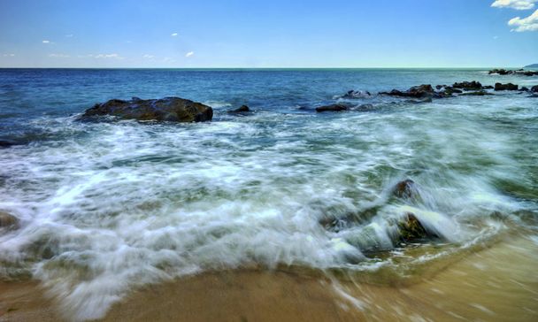 Krásná krajina s kameny a mořské vlny na slunné pláži - Fotografie, Obrázek