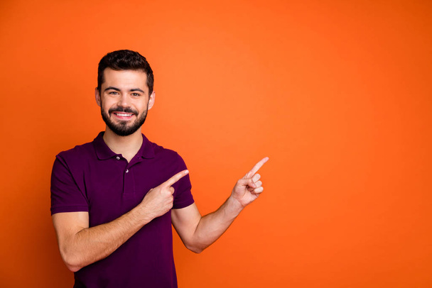 Photo of cheerful trendy handsome man smiling toothily pointing into empty space with brislte on face isolated vivid color background - Photo, Image