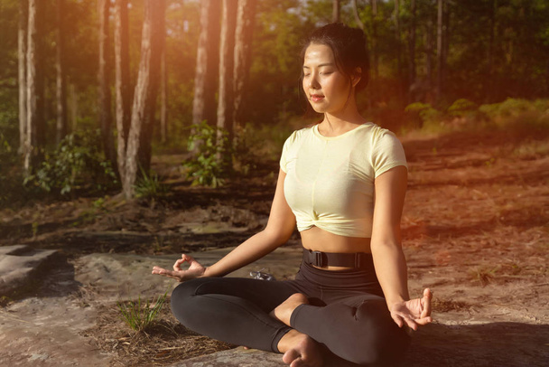 Young beautiful Asian woman practices yoga and meditates outdoor - Photo, Image