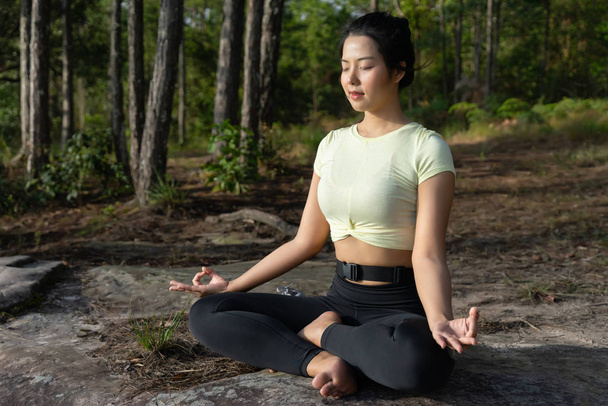 Joven mujer asiática hermosa practica yoga y medita al aire libre - Foto, imagen