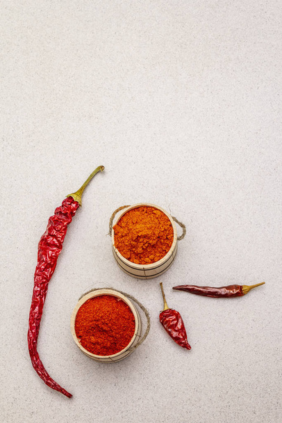 Magyar (Hungarian) red sweet and hot paprika powder. Traditional seasoning for cooking national food, different varieties of dry pepper. Wooden kegs, stone concrete background - Фото, зображення