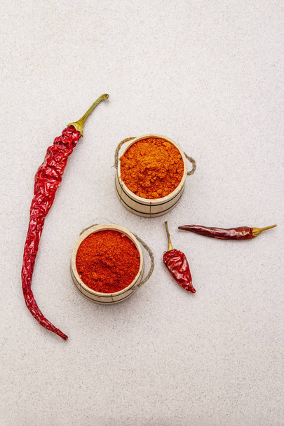 Magyar (Hungarian) red sweet and hot paprika powder. Traditional seasoning for cooking national food, different varieties of dry pepper. Wooden kegs, stone concrete background - Foto, imagen