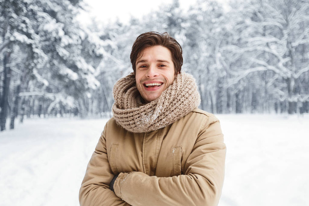Hombre atractivo sonriendo ante la cámara posando en el bosque nevado
 - Foto, Imagen