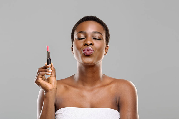 Pretty Afro Woman Holding Pink Lipstick and Sending Air Kiss - 写真・画像