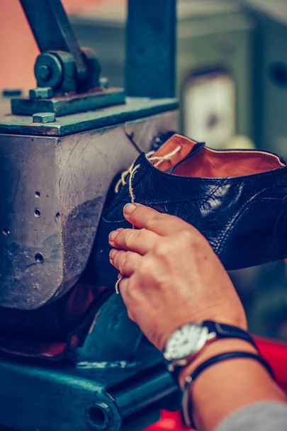 Ervaren schoenmaker met behulp van speciale machine tool voor het maken van een s - Foto, afbeelding