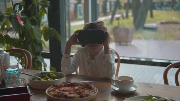 Junge schaut sich beim Mittagessen in Virtual-Reality-Brille um - Filmmaterial, Video