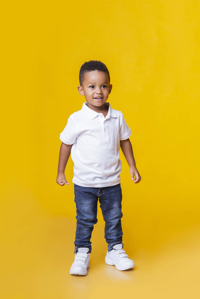 Portret uśmiechniętego czarnego chłopca w dżinsach i białej koszulce - Zdjęcie, obraz