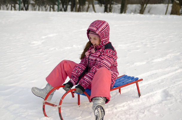 niña en abrigo blanco con trineo en las manos en invierno en la nieve - Foto, imagen