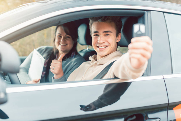 Szczęśliwy student szkoły jazdy pokazując kluczyki samochodowe - Zdjęcie, obraz