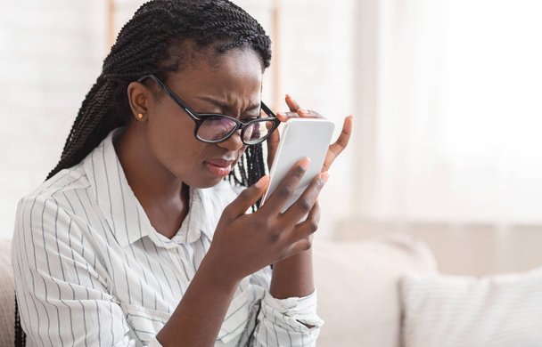 Afro fille regardant l'écran de smartphone à travers des lunettes, ayant un problème de vue
 - Photo, image