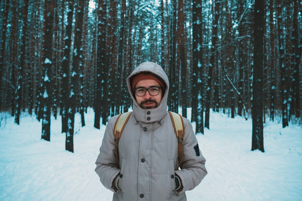 молодой человек стоит в зимнем заснеженном лесу
 - Фото, изображение