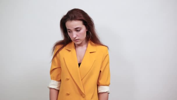 Mujer joven atractiva en chaqueta amarilla cubriendo los ojos con las manos, mirando triste
 - Imágenes, Vídeo