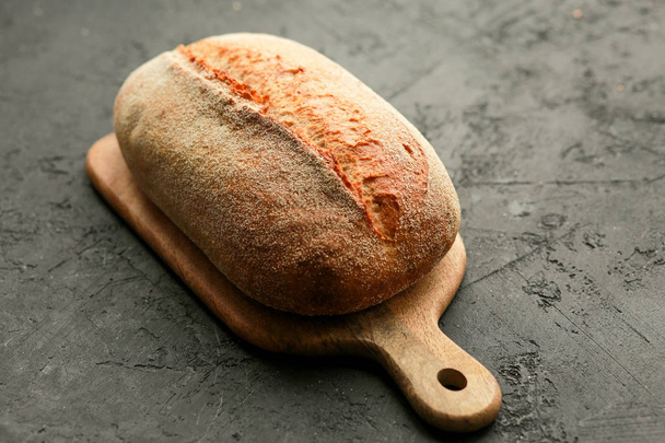 Bread in a basket on a black background. Assorted baking in a metal basket. Place for recipe and text. Background with rolling pin and flour. Rye bread and baguette with seeds. Buckwheat bread  - Photo, Image