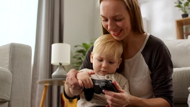 Baby boy with a gamepad sitting on his mother s lap - Video, Çekim
