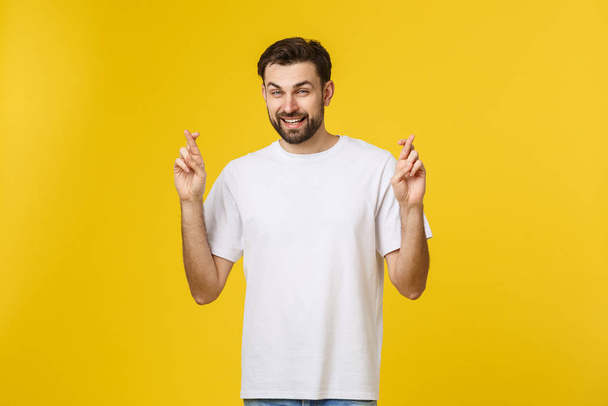 Young man making a wish isolated on yellow background - Photo, Image