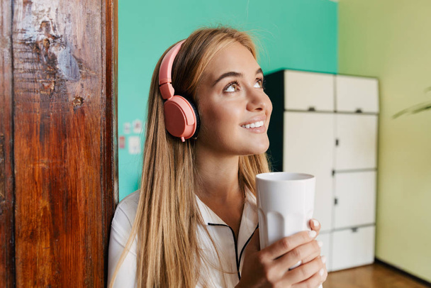 Cute girl in pajama at home listening music with headphones. - 写真・画像