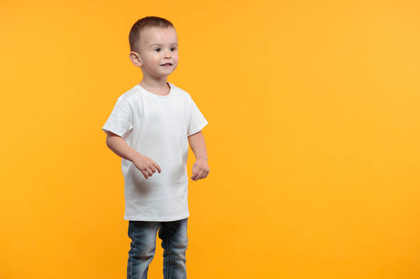 Kid boy wearing white t-shirt with space for your logo or design over yellow background - Foto, immagini